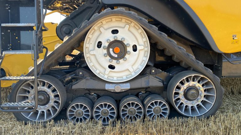 Detailed view of a tracked vehicle's wheels on a harvested field in Ukraine.