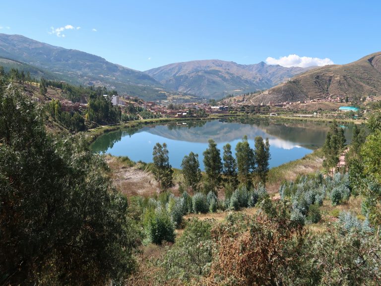 A picturesque view of a serene mountain lake surrounded by lush greenery and hills.