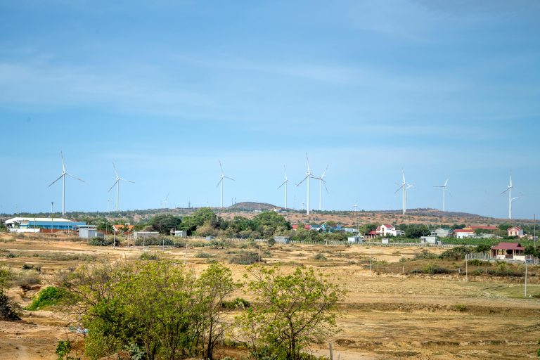 Wind turbines standing tall in a rural landscape with a clear sky, highlighting renewable energy.