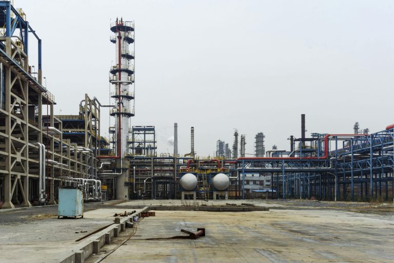 A detailed view of an industrial refinery featuring pipelines and large steel structures.