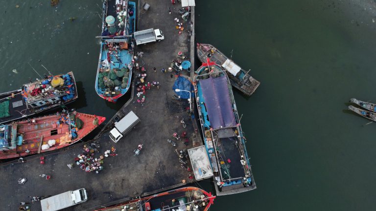 Aerial view of colorful fishing boats docked at Thuận An, Vietnam, bustling with activity.