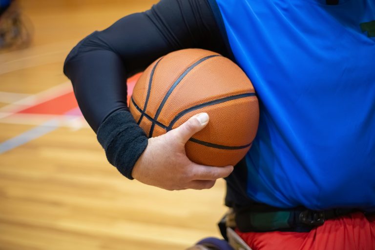 A close-up image of a basketball player holding a ball during a game, showcasing focus and determination.