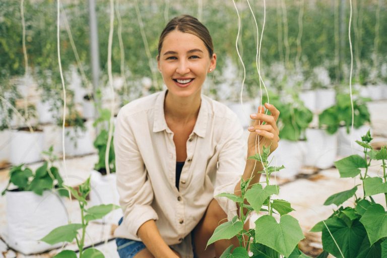 Smiling woman in a greenhouse showcasing modern indoor farming techniques.