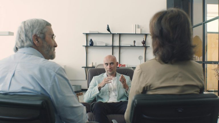 Therapist holding a session with an elderly couple discussing mental health in a professional office setting.