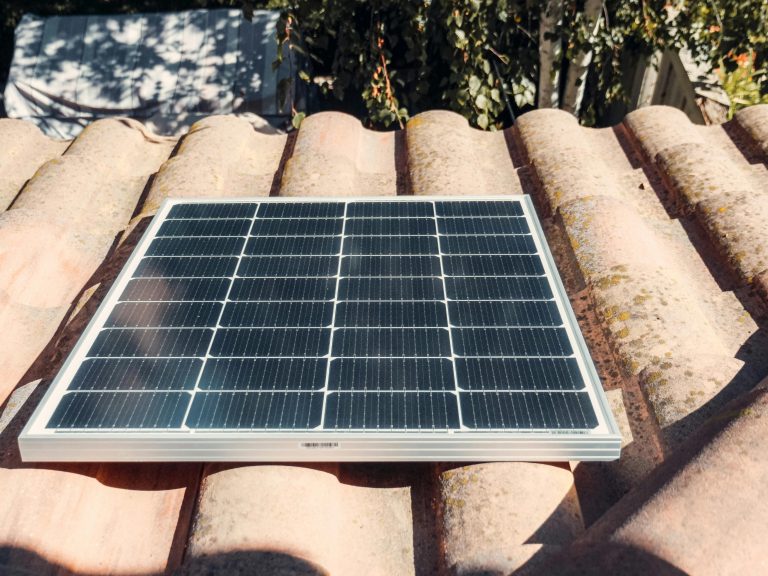 A single solar panel on a rustic tiled roof gleaming in sunlight. Eco-friendly energy.